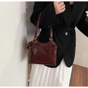 Detail of vintage burgundy leather underarm bag with retro metallic charm on model