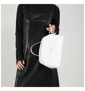 Détail d'un sac oreiller en cuir blanc avec texture litchi et lettrage doré chic