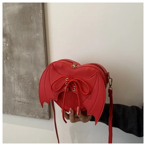 Detail of red heart-shaped gothic bag featuring black bat wings and lace-up strap design