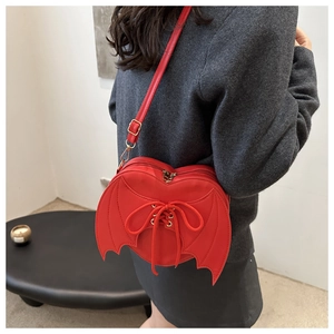 Detail of red heart-shaped bat wing bag with lace-up design and metal hardware on model