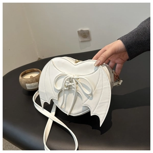Detail of white heart-shaped bag with gothic bat wings and decorative cross-lacing design
