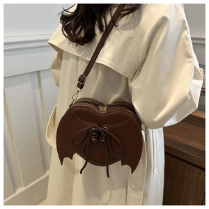 Detail of dark brown heart-shaped bag with bat wings and lace-up gothic design