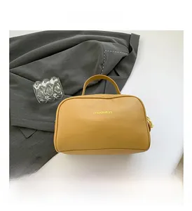 Close-up of bright yellow litchi grain leather pillow bag with top handle and logo