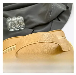 Detail of lychee textured leather pillow bag with sturdy handle and precise stitching