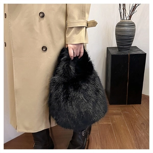 Close-up of black faux fox fur handbag held by model in elegant beige trench coat