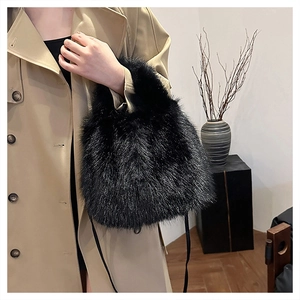 Detail of soft black faux fur handbag with leather strap on trench coat model