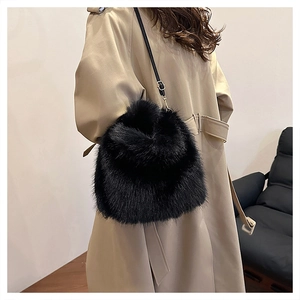 Detail of black faux fox fur bucket bag with leather strap on a trench coat