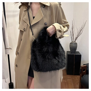 Detail of black faux fur bucket bag with plush texture and slim leather shoulder strap