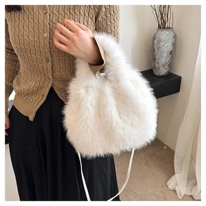 Detail of soft white faux fox fur handbag with a thin shoulder strap in a cozy home setting