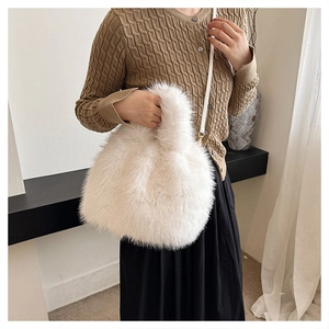 Close-up of white faux fox fur bag with soft texture and golden metal strap hooks