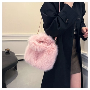 Pink faux fox fur bucket bag with leather strap shown against a black blazer