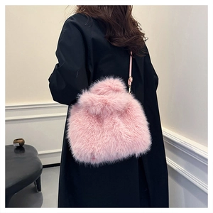 Chic pink faux fox fur crossbody bag styled with a long black wool coat in a street setting