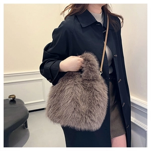 Brown faux fur handbag shown on a model with a leather shoulder strap and soft texture