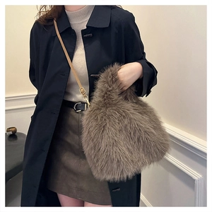 Detail of soft brown faux fur handbag with adjustable leather shoulder strap and gold hardware