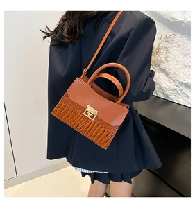 Borsa patchwork marrone con trama a coccodrillo mostrata sulla spalla di una modella