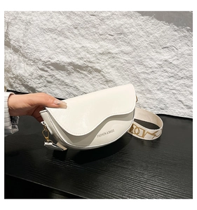Close-up of white semi-circle saddle bag with branded fabric strap and fashion text
