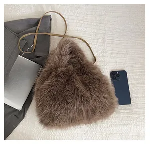 Close-up showing the size of the brown faux fur crossbody bag next to a smartphone