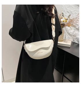 Detail view of cream saddle bag with jacquard strap worn by a model in a minimalist room