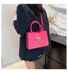 Dettaglio borsa fucsia con texture a coccodrillo e chiusura quadrata in metallo oro