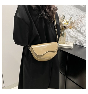 Detail view of the apricot saddle bag showing gold lettering and metal chain strap