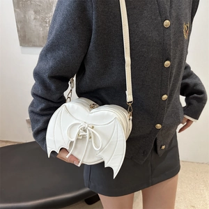 White heart-shaped crossbody bag with bat wings and lace-up bow design on model