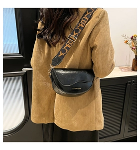 Detail showing the black glossy saddle bag and its adjustable wide jacquard strap