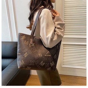 Detail shot of a large brown leather tote bag with stylish all-over letter printing