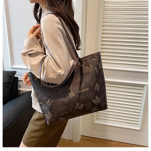Close-up of monogram print details and gold brand logo on deep brown leather tote bag