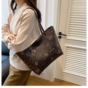 Close-up of a large printed tote bag featuring a brand monogram pattern and twin handles