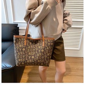Detail view of large brown monogram tote bag with leather straps and printed letters