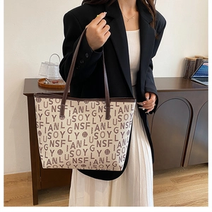 Close-up of a printed tote bag with leather straps worn by a model in casual attire