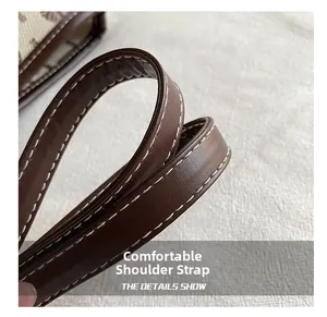 Detail view of the brown leather shoulder strap with neat white contrast stitching