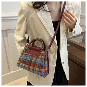 Détail d'un sac à main vintage à carreaux avec poignée en bois ronde et bandoulière sur blazer