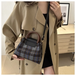 Détail du sac en laine à carreaux avec poignée ronde en bois et trench-coat kaki