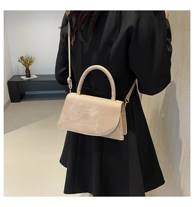 Beige minimalist crossbody handbag styled with a shoulder strap on a model's back