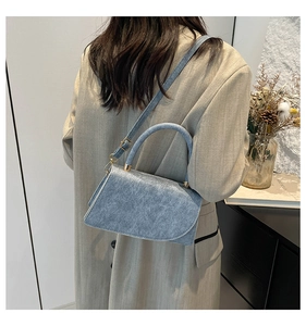 Close-up of light blue trapezoid handbag with gold hardware and adjustable strap