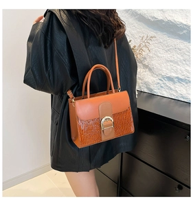 Vue détaillée du sac à main orange à motif crocodile montrant la boucle dorée et le cuir