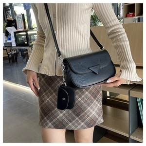 Détail du sac à bandoulière en cuir noir à motif litchi avec petit porte-monnaie assorti