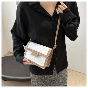 Detail of a white faux crocodile texture small crossbody bag with khaki trim on a model