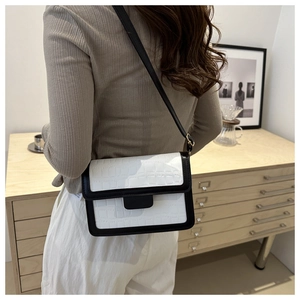 Minimalist white crocodile texture crossbody bag with black trim worn by a model