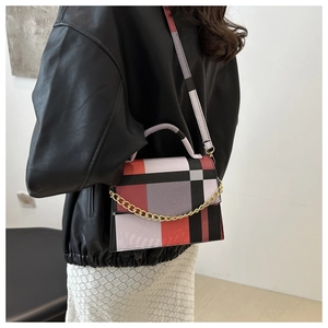 Detail of a geometric color-block crossbody bag with gold chain and wide patterned strap
