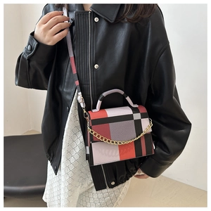 Detail of color-block flap bag with golden chain strap on a black leather jacket