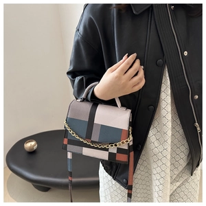 Detailed shot of multi-color patchwork plaid handbag with gold chain accent and leather texture