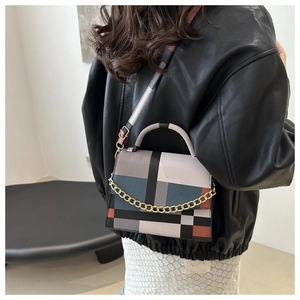 Detail of color-block geometric handbag with gold chain accent and leather texture