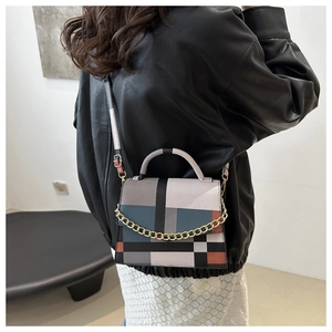 Detail view of stylish color-block small square bag with metal chain and top handle strap