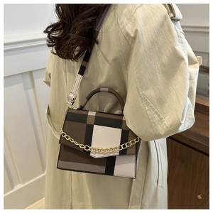 Detailed view of plaid handbag with gold chain strap on a trench coat model