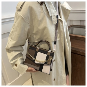 Detail view of plaid crossbody bag featuring tricolor pattern and gold chain decoration