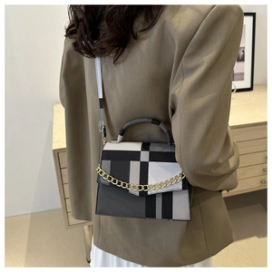 Detail of geometric pattern crossbody bag with gold chain strap on a khaki blazer