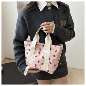 Detail of pink corduroy tote bag with strawberry print and white canvas handles
