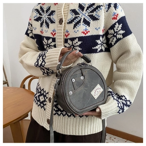 Vue détaillée du sac rond en denim patchwork avec bandoulière réglable et poignée de port